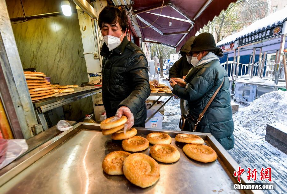 乌鲁木齐市文化路,已开门营业的馕店吸引过往市民前来购买。 刘新 摄 乌鲁木齐市文化路,已开门营业的馕店吸引过往市民前来购买。 刘新 摄